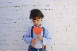 photo of boy holding heart shape paper on stick